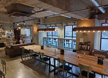 Cafe interior with long wooden tables, chairs, and sofa seating
