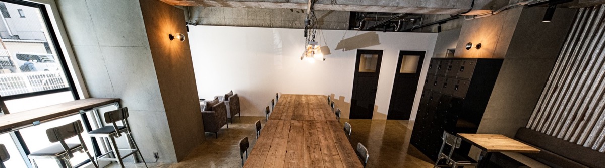 Cafe interior with a long wooden table, window seats, and sofa seating